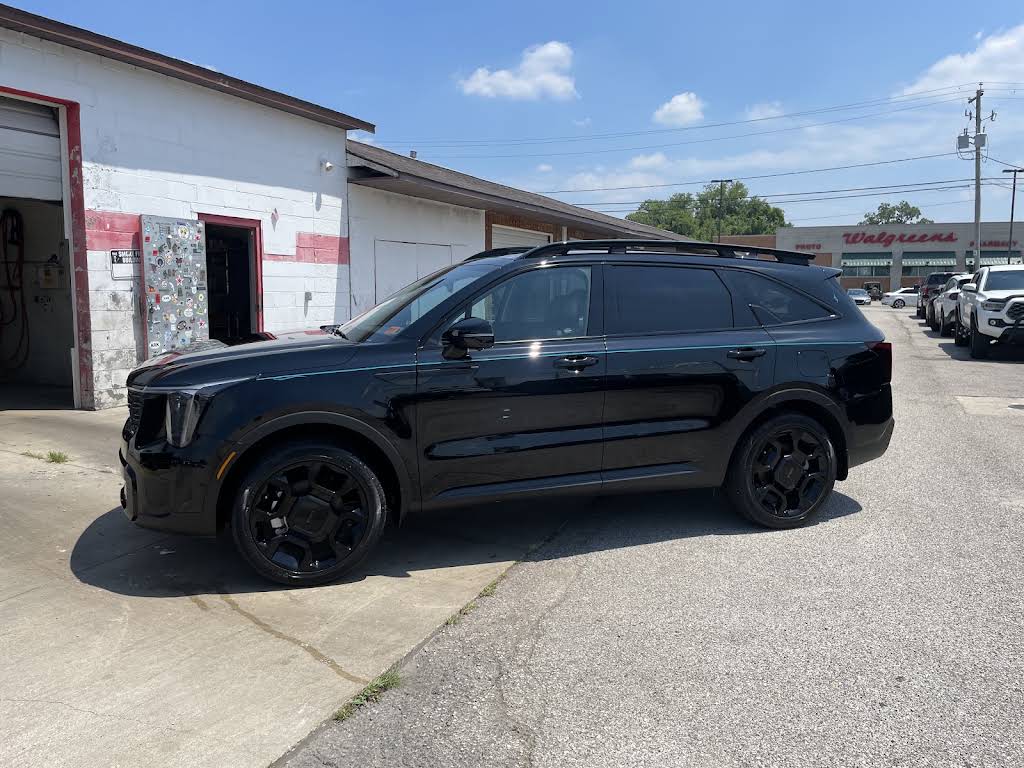 Gloss-black SUV freshly detailed, parked outside the shop in Milton