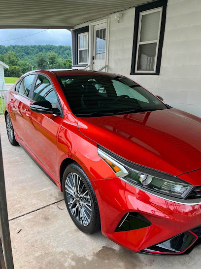 Red sedan with a wet-look finish parked under a carport